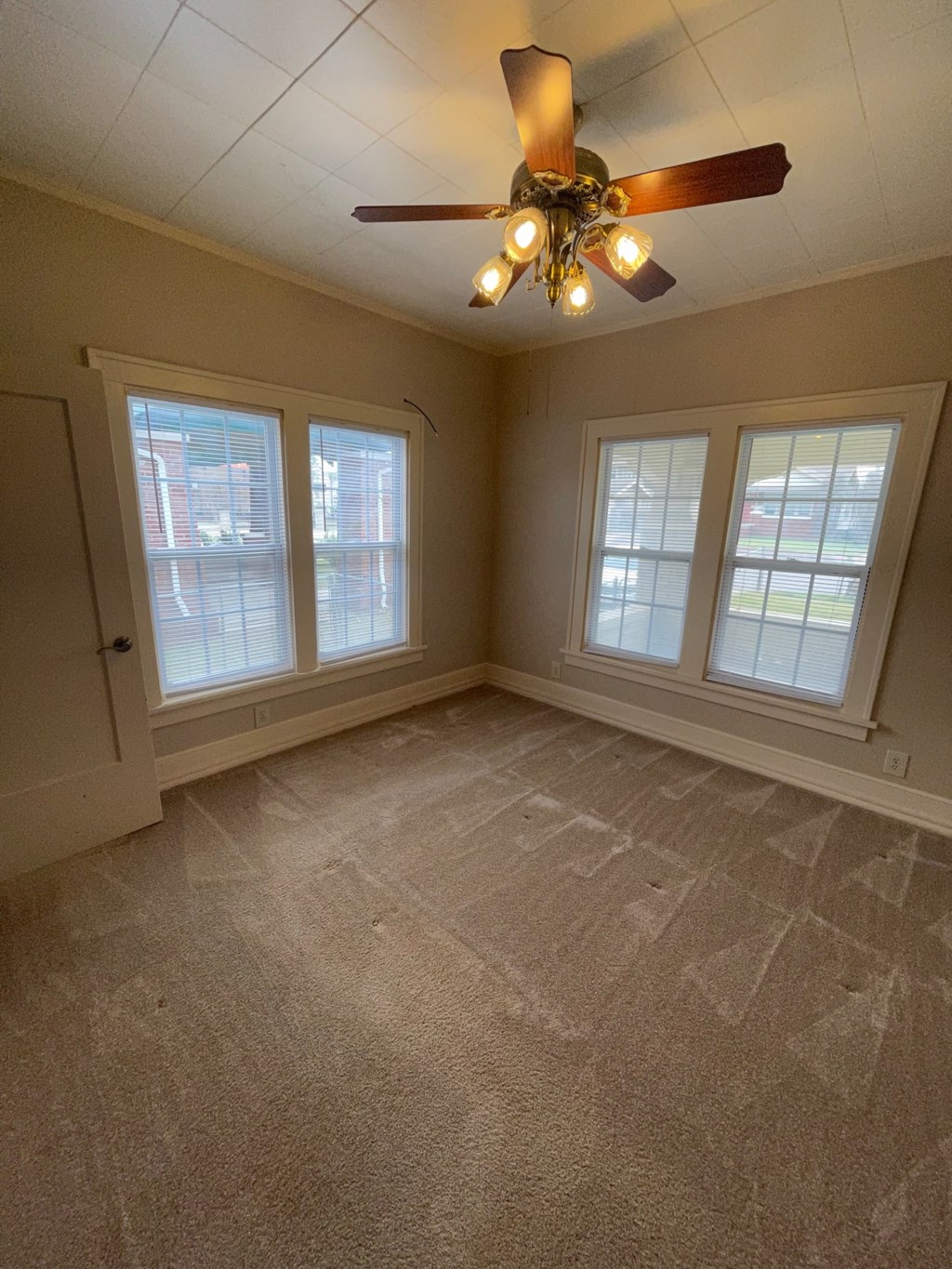 a living room with a ceiling fan and three windows
