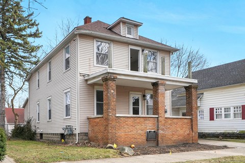 the front of a house with a brick facade and white siding