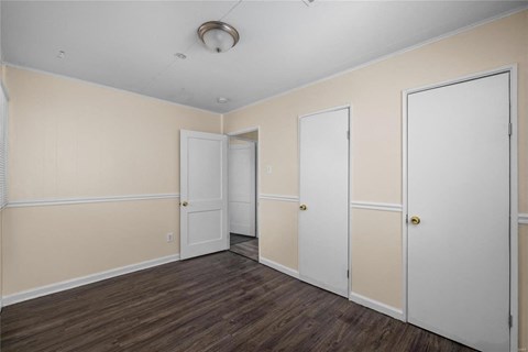 a bedroom with white walls and doors and a wood floor