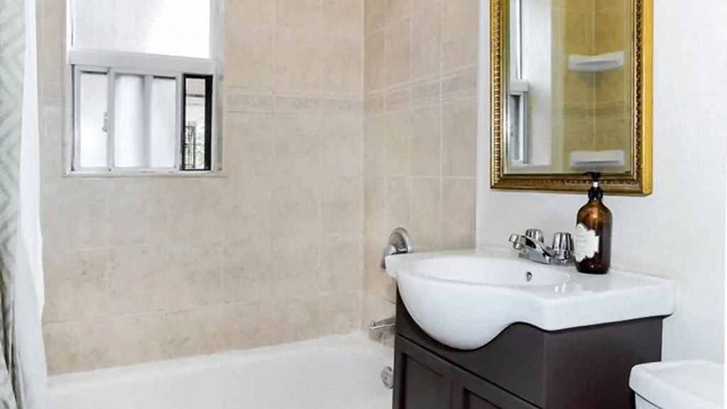 the bathroom has a shower and a sink and a mirror