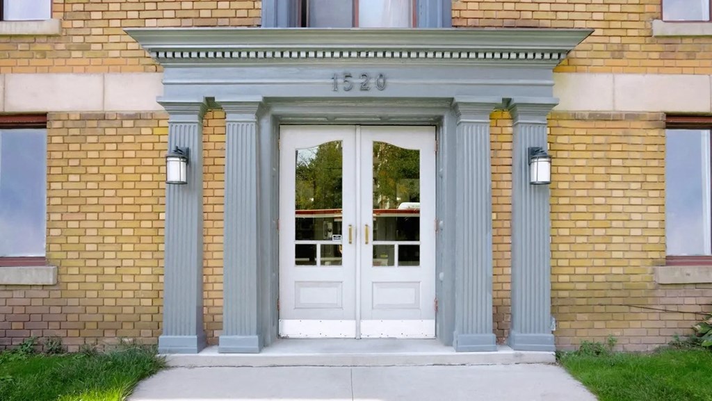 the front door of a brick building with blue columns