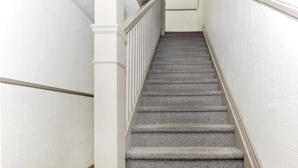 a carpeted staircase with white railings and grey carpeted stairs