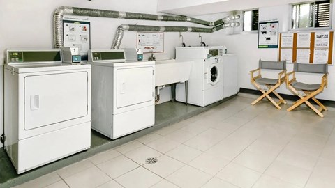 a laundry room with four washing machines and folding chairs