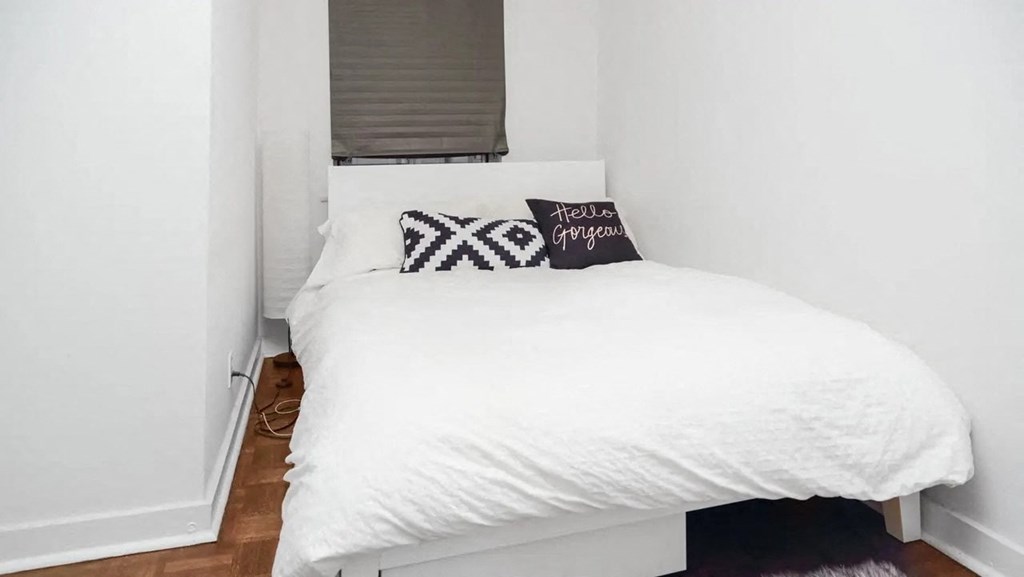 a small bedroom with a white bed and a window