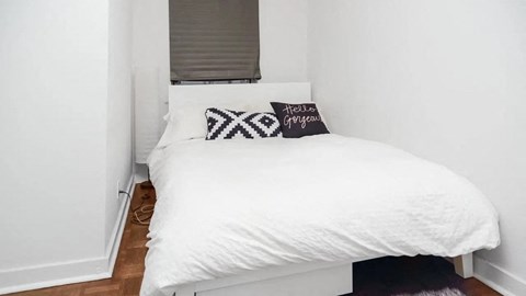 a small bedroom with a white bed and a window
