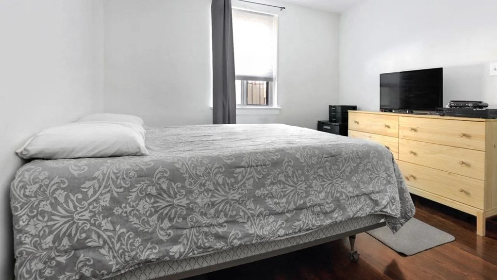 a bedroom with a bed and a dresser with a television