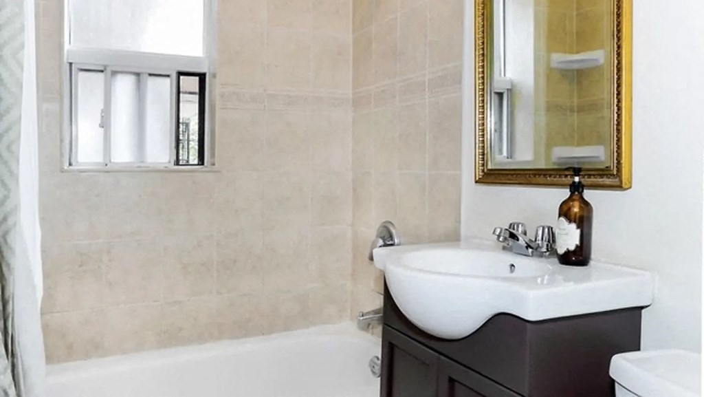 the bathroom has a shower and a sink and a mirror