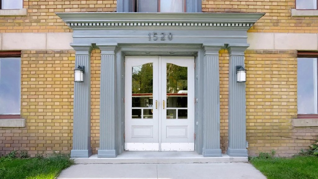 the front door of a brick building with blue columns