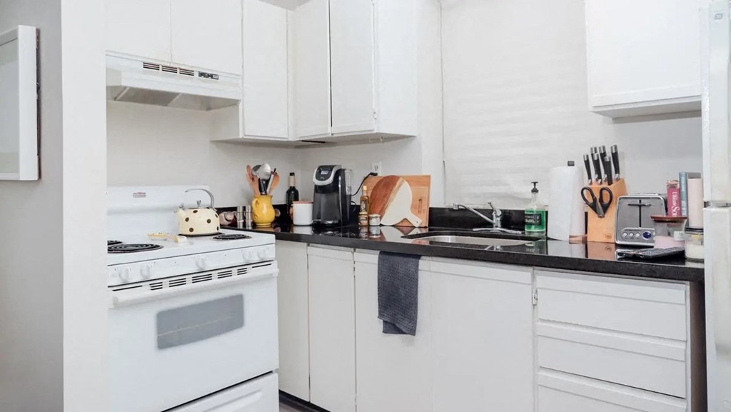 a white kitchen with white appliances and black counter tops