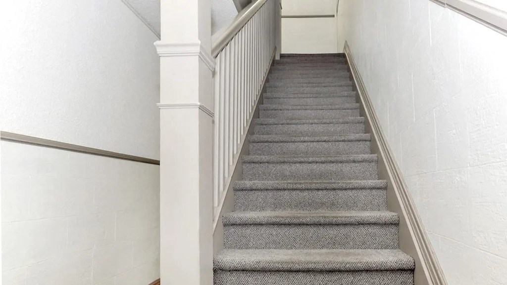 a carpeted staircase with white railing and gray carpeted stairs