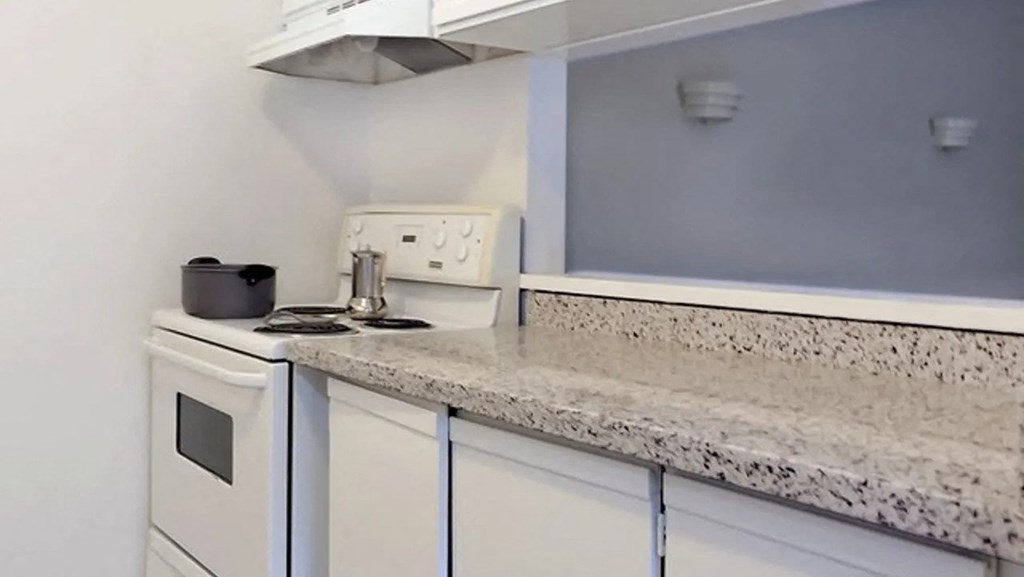 a kitchen with white cabinets and a counter top and a stove