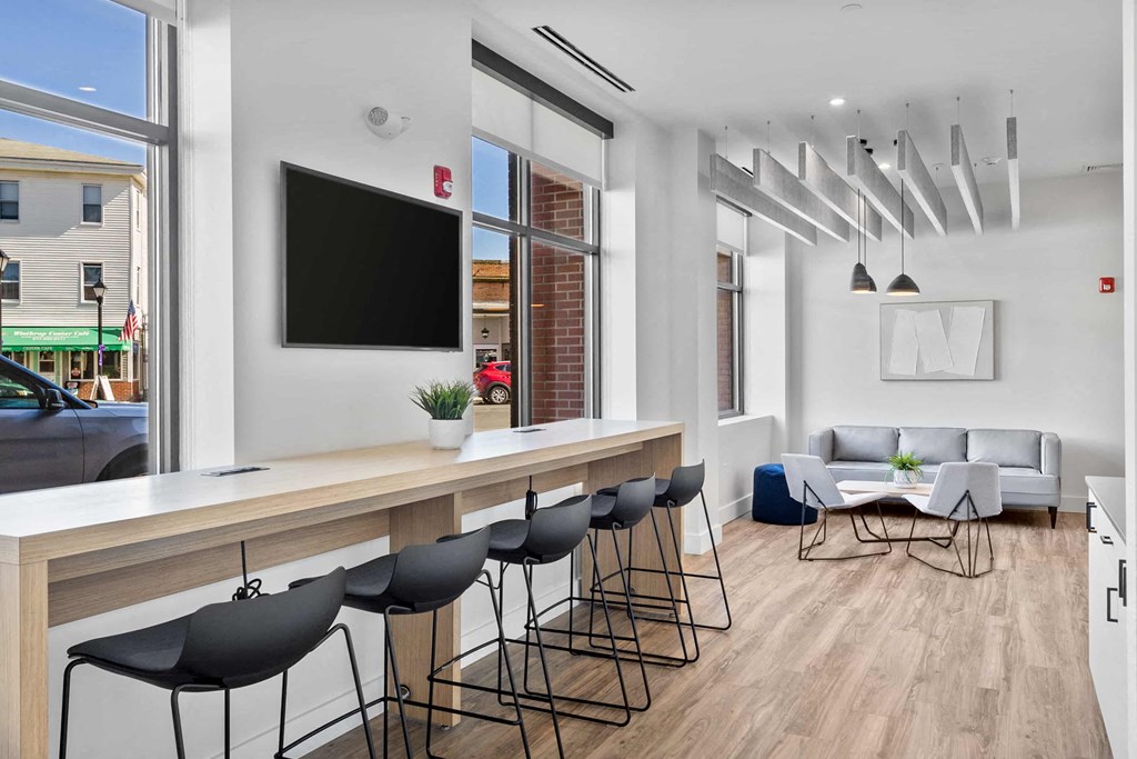 a room with a bar and a living room with chairs