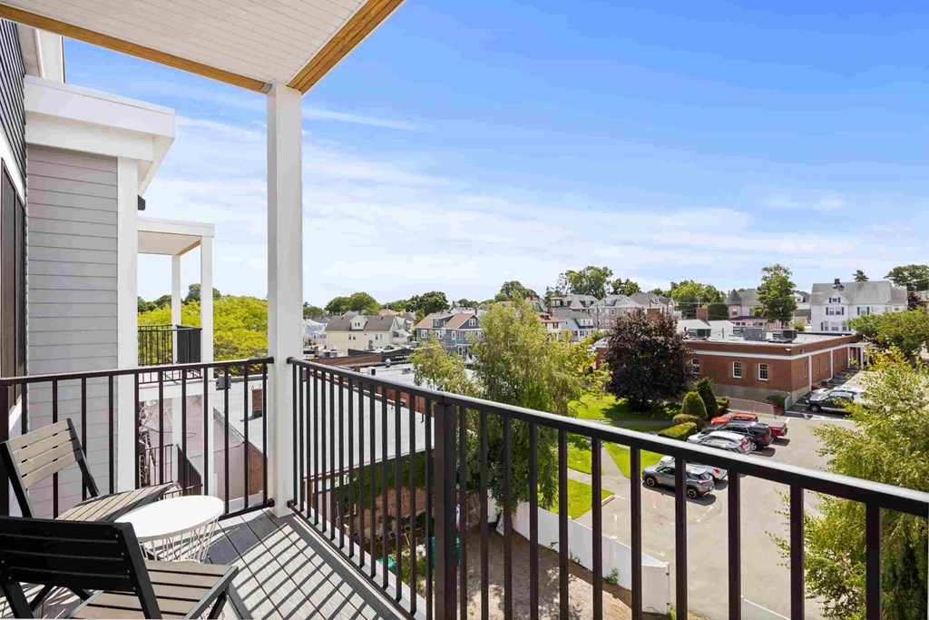 a balcony with a view of a neighborhood and a patio with chairs