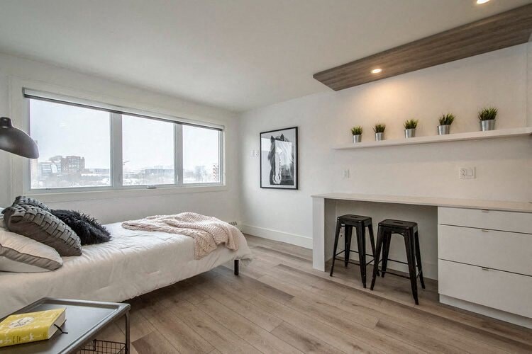 a bedroom with a bed and a desk and two bar stools