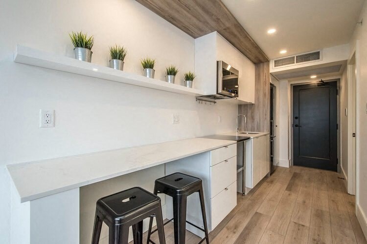 a kitchen with two black stools in front of a counter
