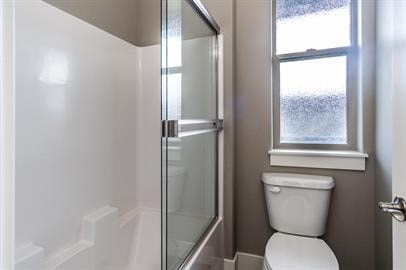 A white toilet sits next to a glass shower stall in a bathroom.