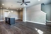A spacious room with a ceiling fan and a dark wood floor.