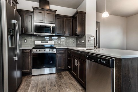 A modern kitchen with dark wood cabinets and stainless steel appliances.