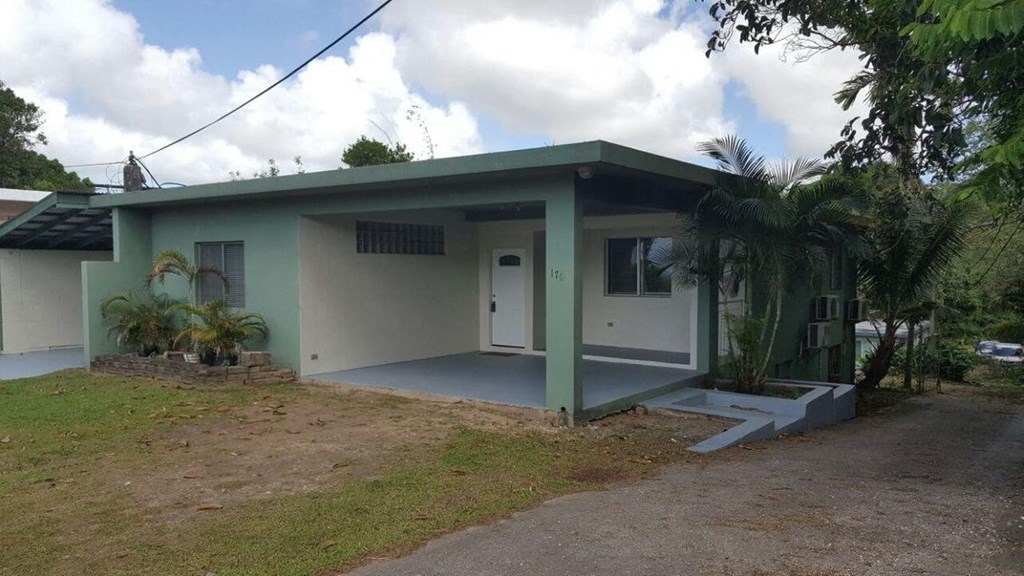 a small house with a porch and a palm tree