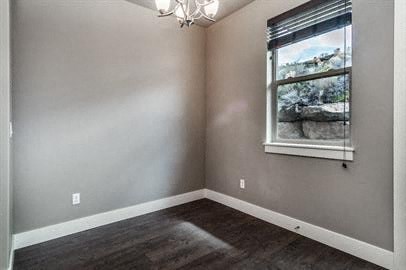 an empty room with a window and wooden floors