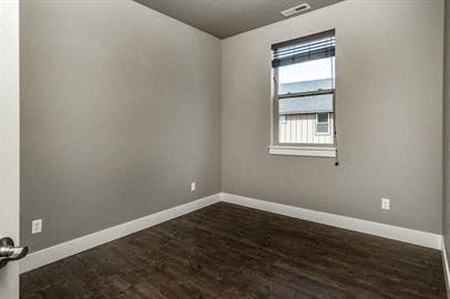 an empty bedroom with a window and wooden floors