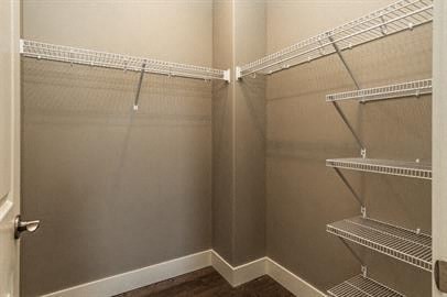 a walk in closet with empty shelves and a door