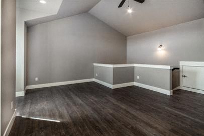 a empty living room with wood floors and a ceiling fan