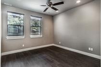 A room with a ceiling fan and two windows.