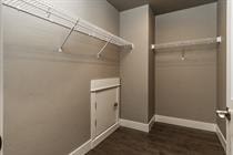 A walk in closet with a white door and brown carpet.