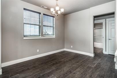A room with wooden flooring and a chandelier.