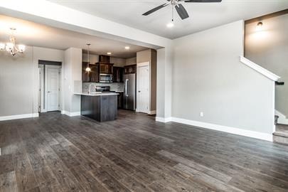 A spacious living room with a kitchen in the background.