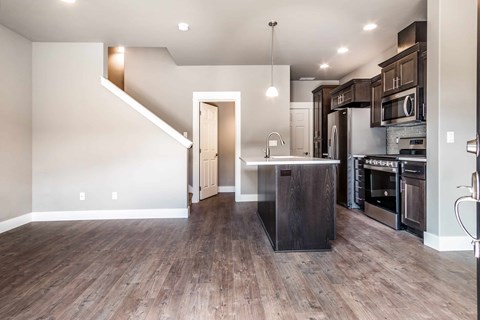 A kitchen with a wooden floor and a staircase.