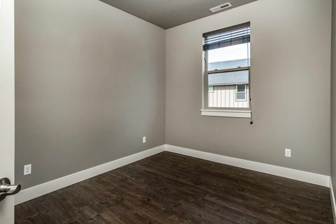 A room with a window and wooden flooring.