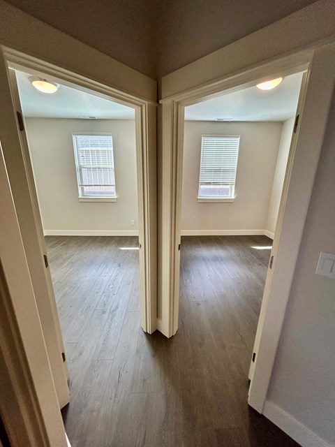 A room with two windows and wooden floors.