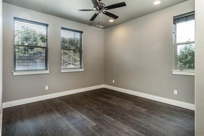 A room with a ceiling fan and two windows.