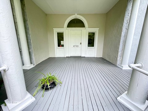 the front entrance of a house with a white door and pillars
