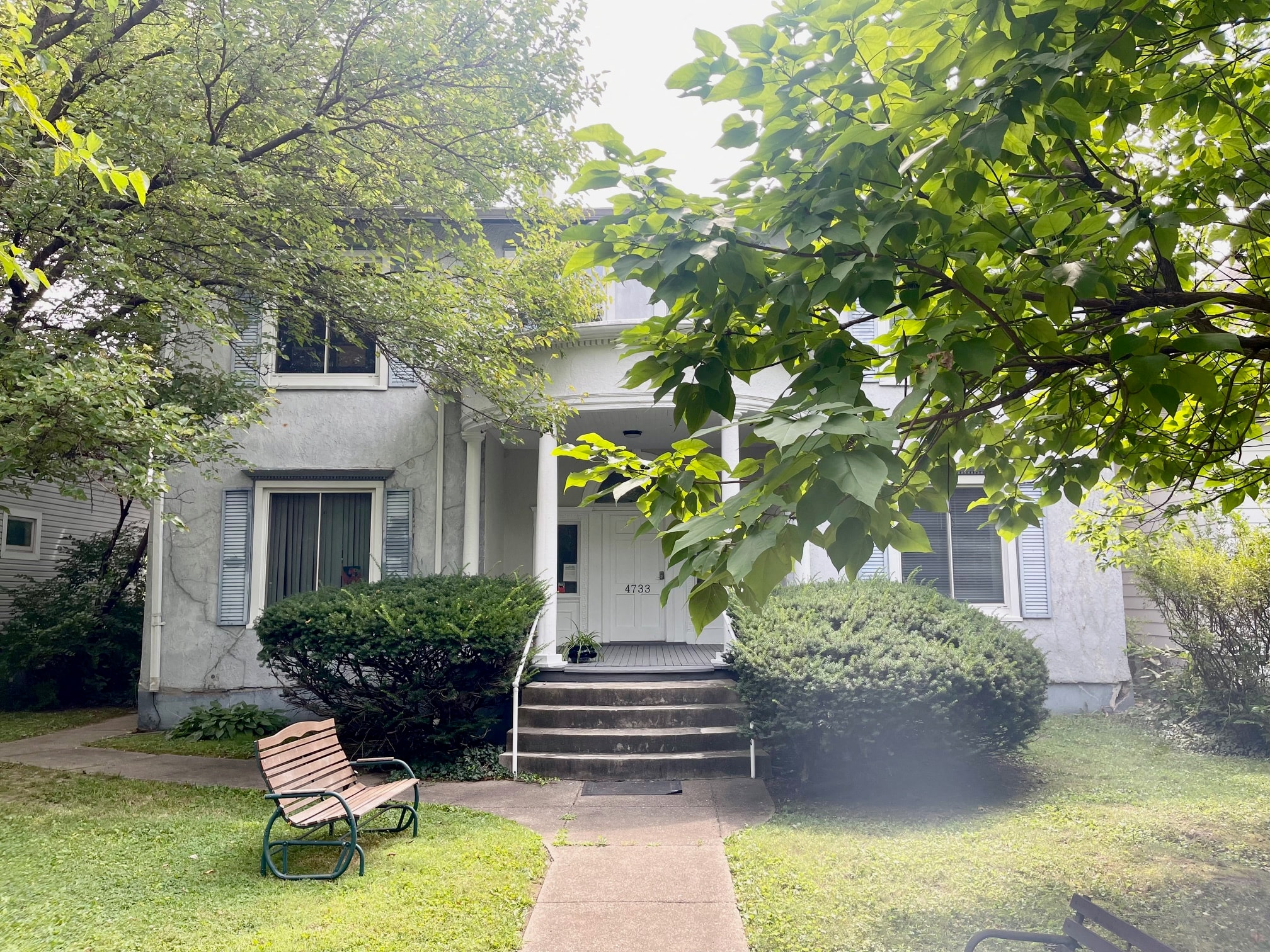a small white house with a yard and a bench