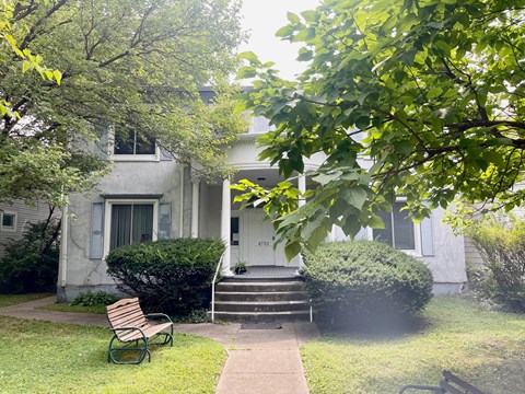 a small white house with a yard and a bench