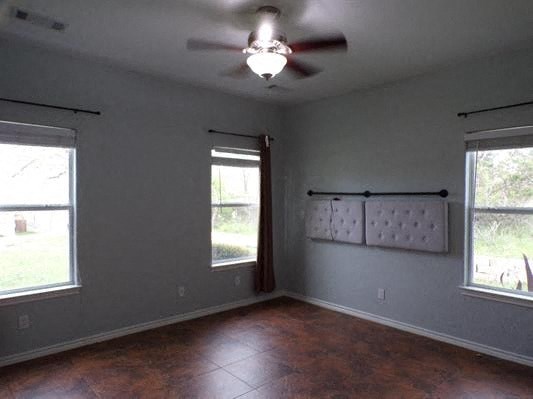 an empty living room with a ceiling fan and two windows