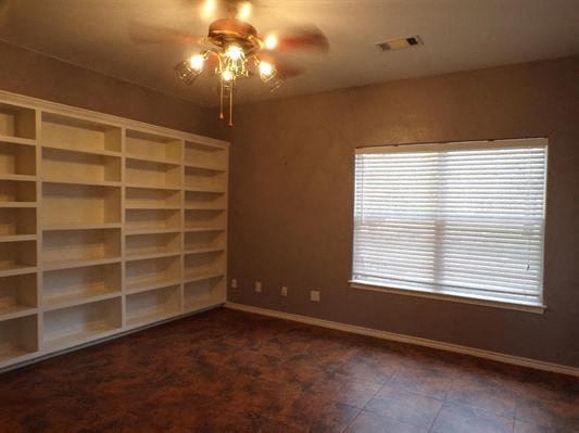 a living room with shelves and a ceiling fan