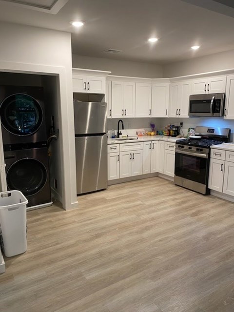A kitchen with white cabinets and a wooden floor.