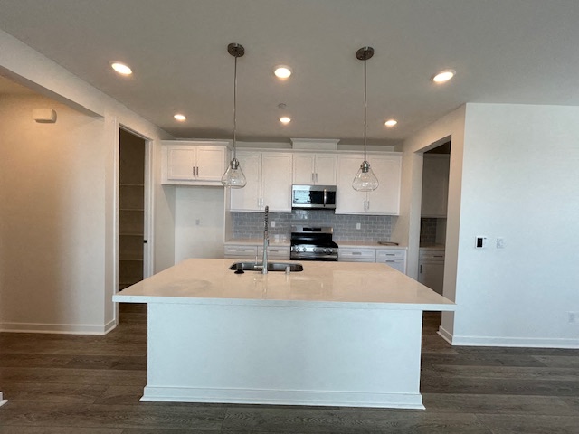 an empty kitchen with a white counter top