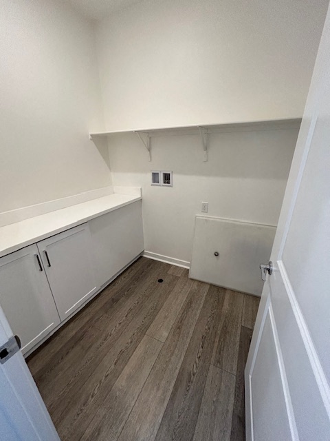 an empty room with white cabinets and a wooden floor