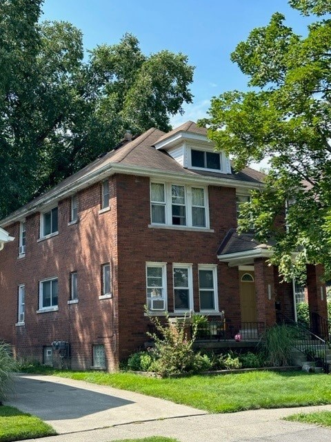 A red brick house with a yellow door and a green lawn in front.