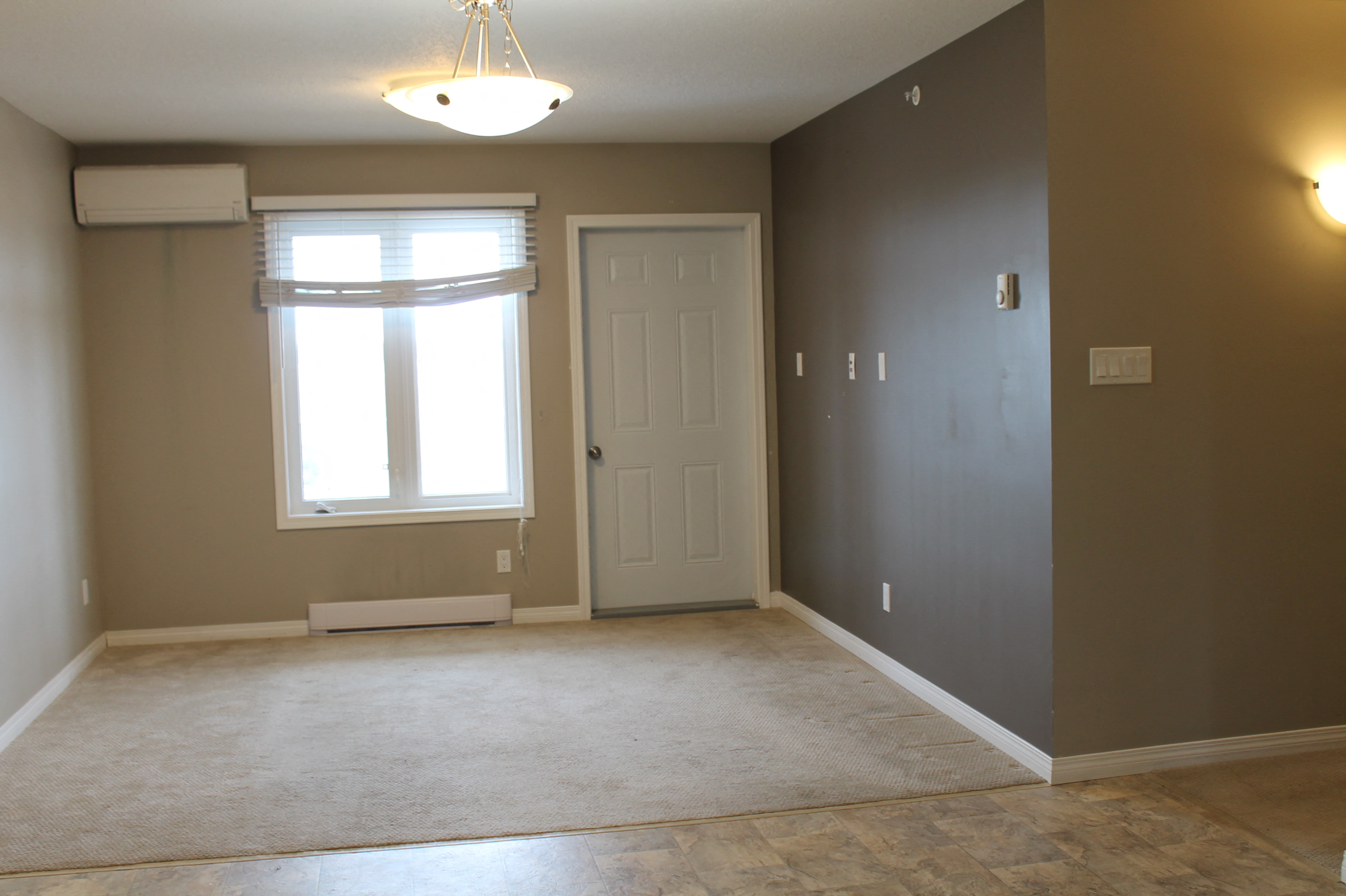 an empty living room with a window and a door