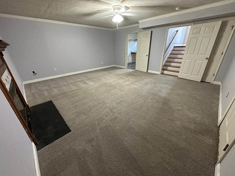 a living room with a carpeted floor and a staircase