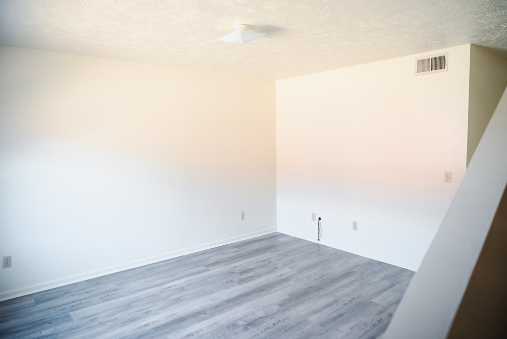 an empty room with white walls and a wood floor