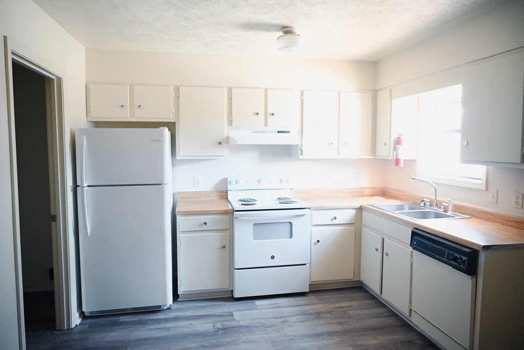 an empty kitchen with white appliances and white cabinets