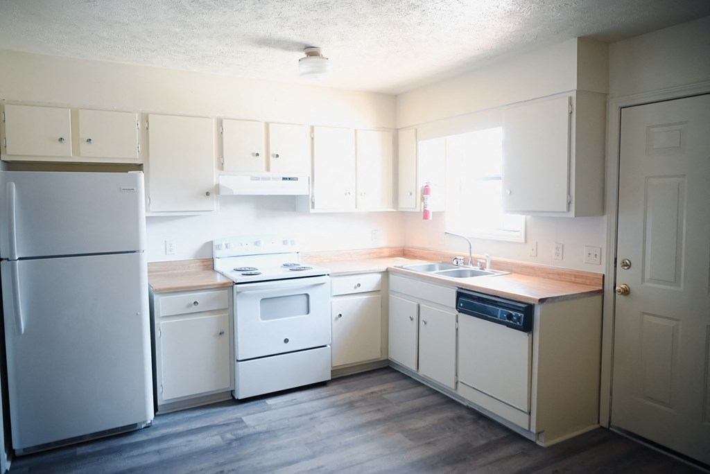 an empty kitchen with white appliances and white cabinets