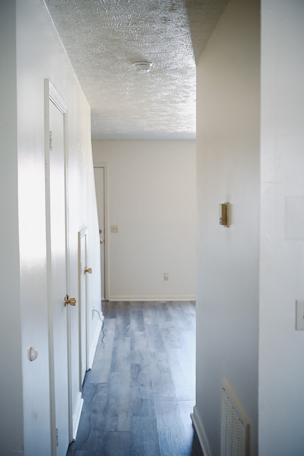 an empty hallway with white walls and wood floors